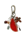 Keychain with red stone and metal charms on a white fabric background